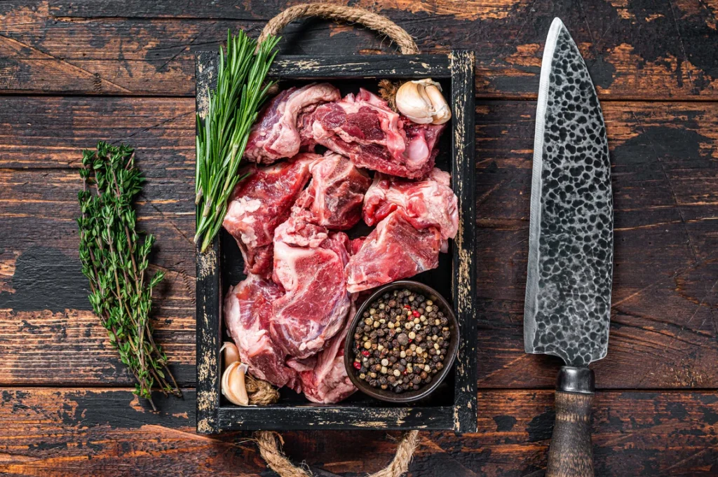 red meat in a pan next to a knife