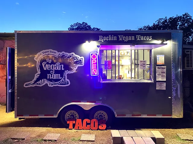 a small light black color food truck photographed at night