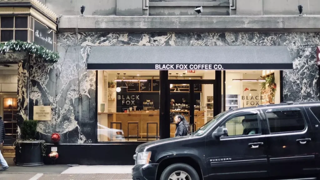 a black color car infront of a coffee shop