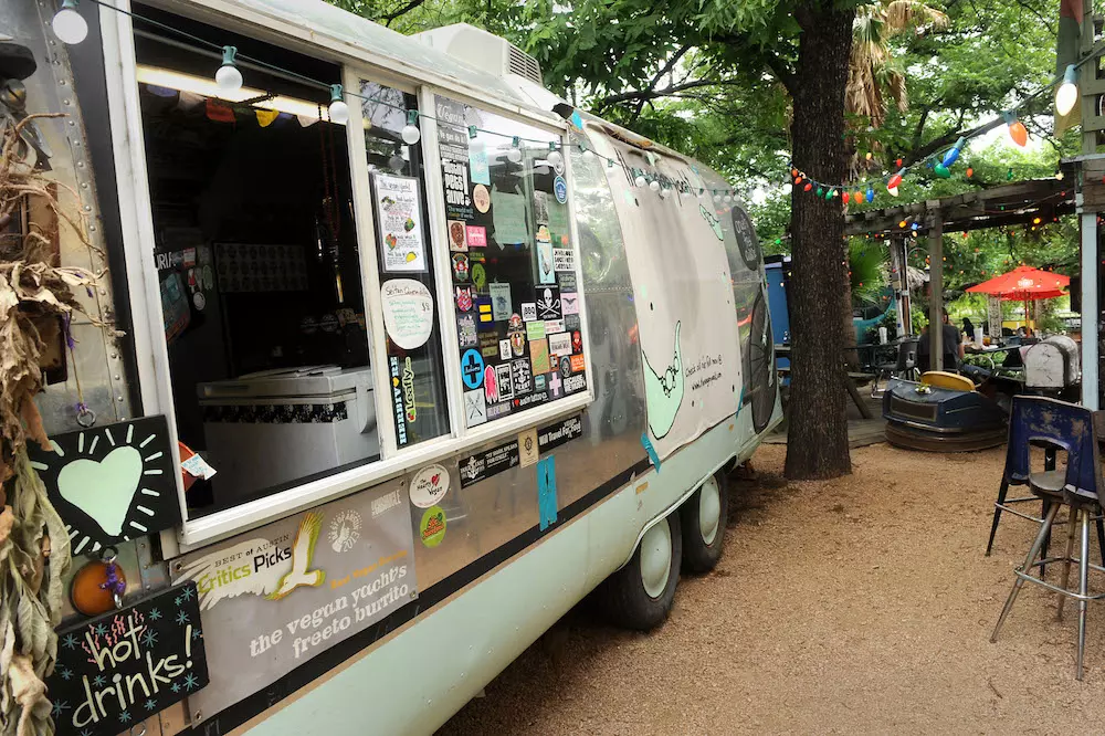 a grey food truck parked in a park