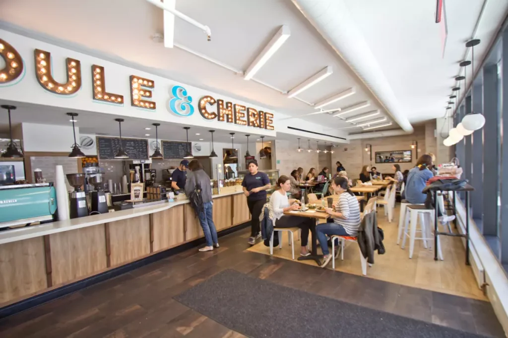 a white color restaurant bar with people waiting for their orders infront of it