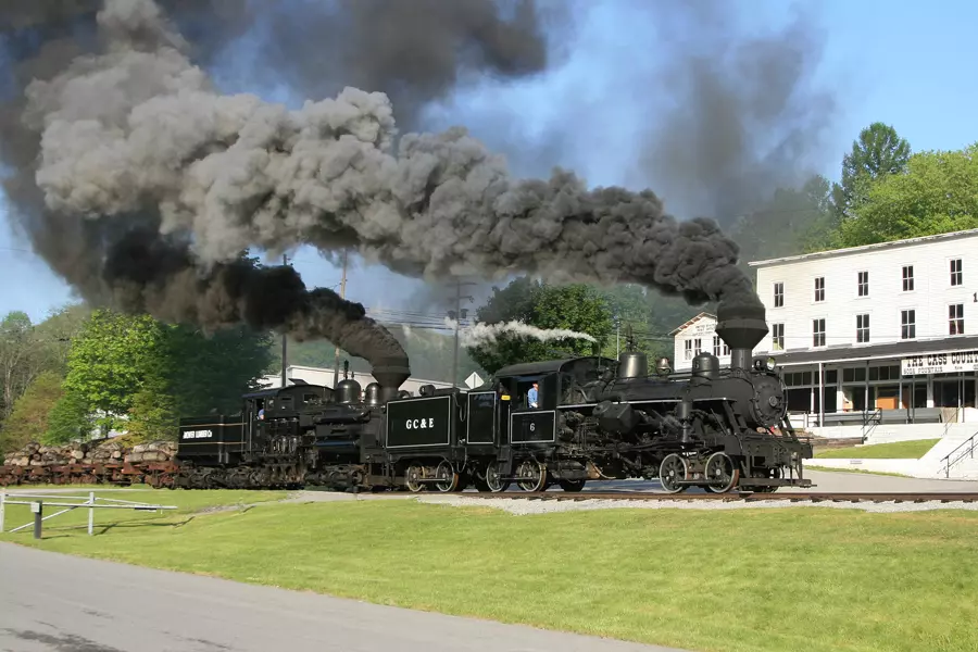 a train passing some white houses and green fields