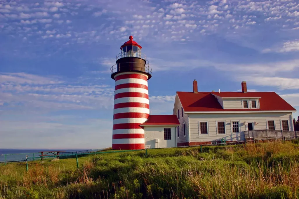 red and white lighthouse near a house on a cliff