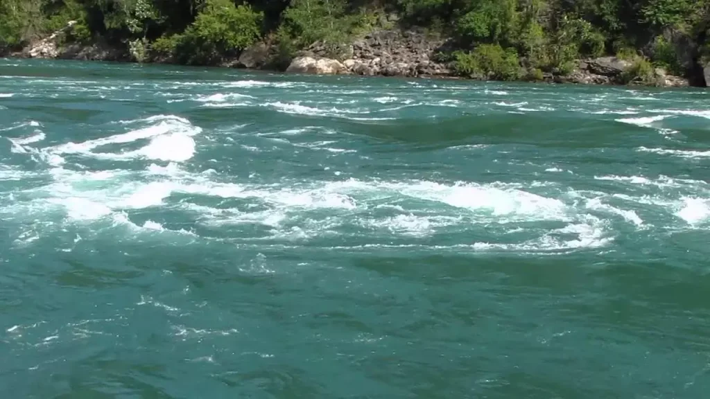 a blue river with rocks next to it