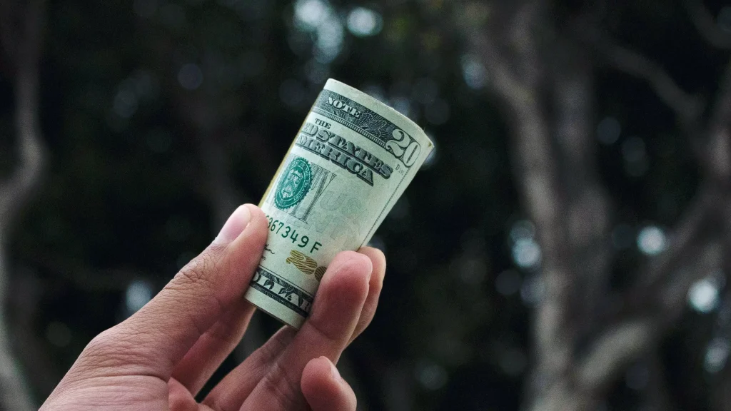 a person holding a rolled dollar bill