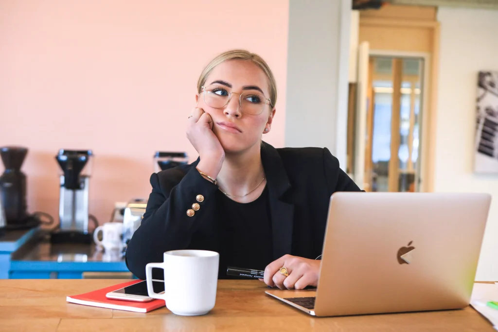 a women with glasses siting behind her desk working on her laptop