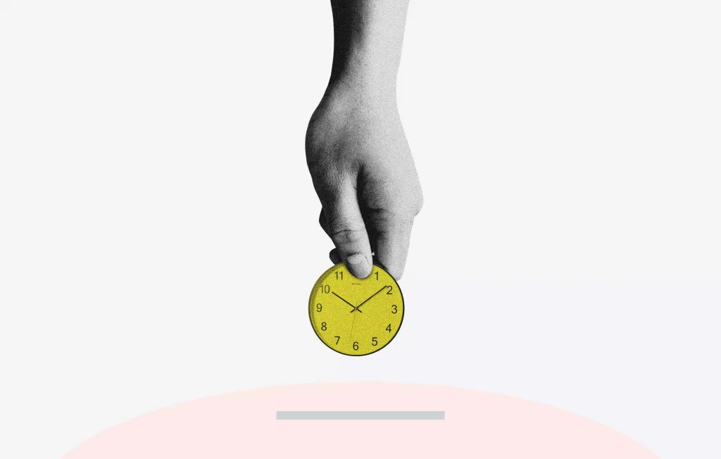 a hand holding a small yellow clock