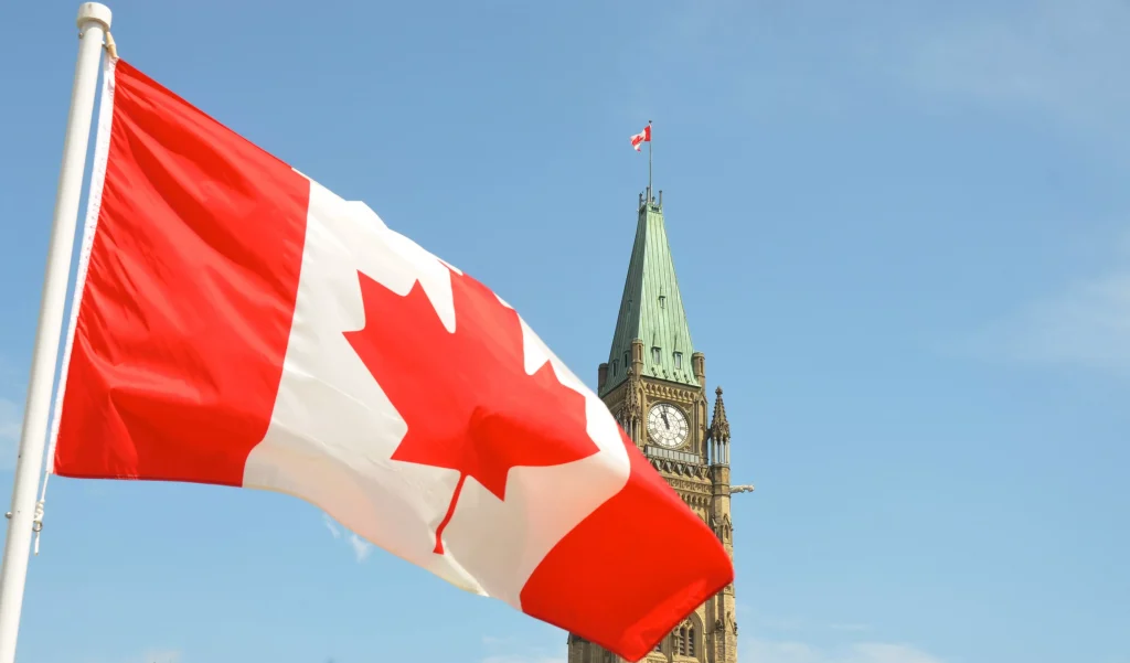 a red and white flag infront of a big tower clock