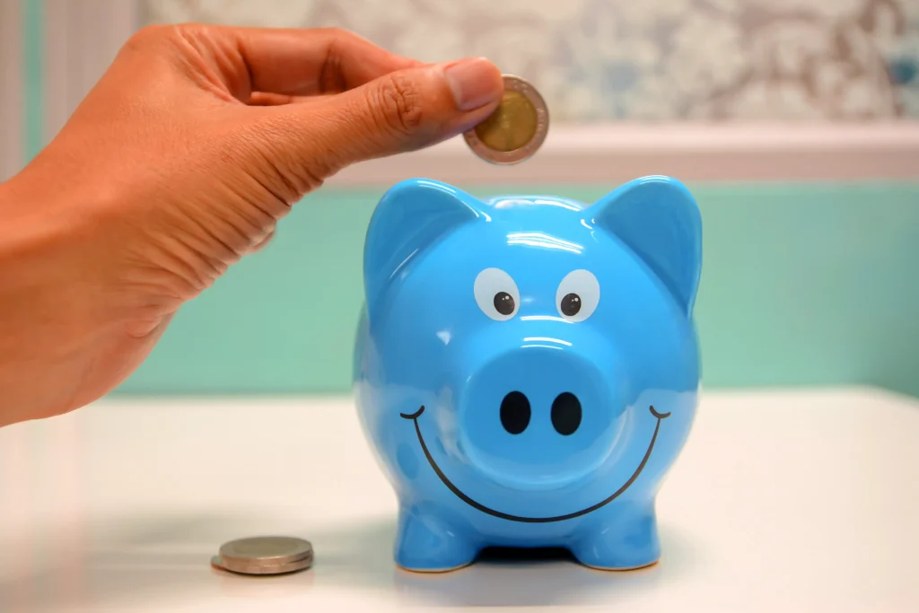 a person putting a coin in a blue piggybank