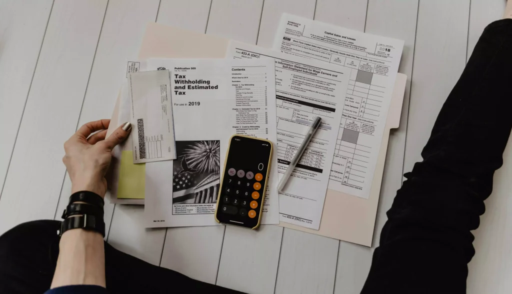 a person reading from some papers while having a calculator opened on the phone