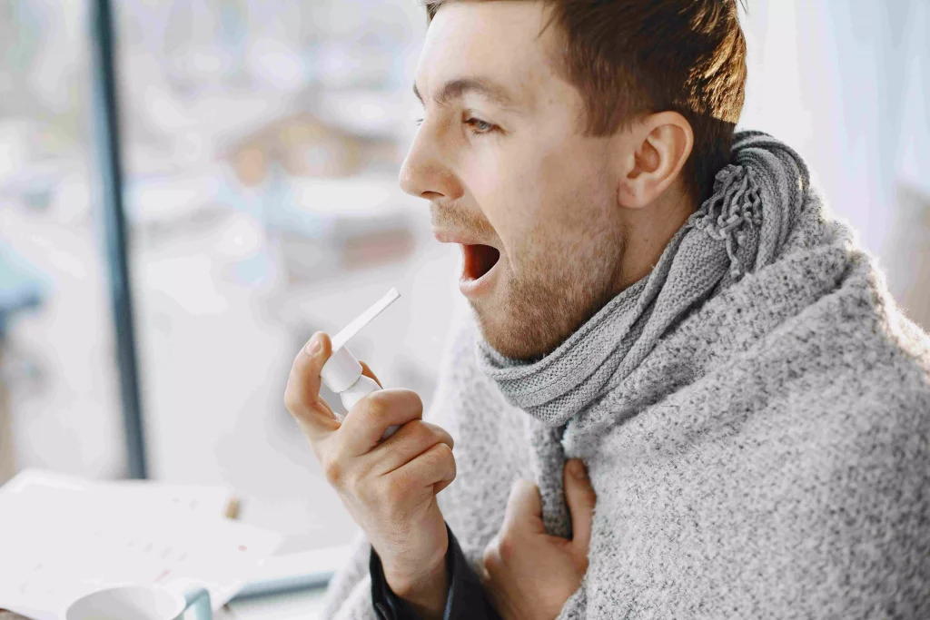 a man wrapped up in a blanket putting toothpaste in his mouth