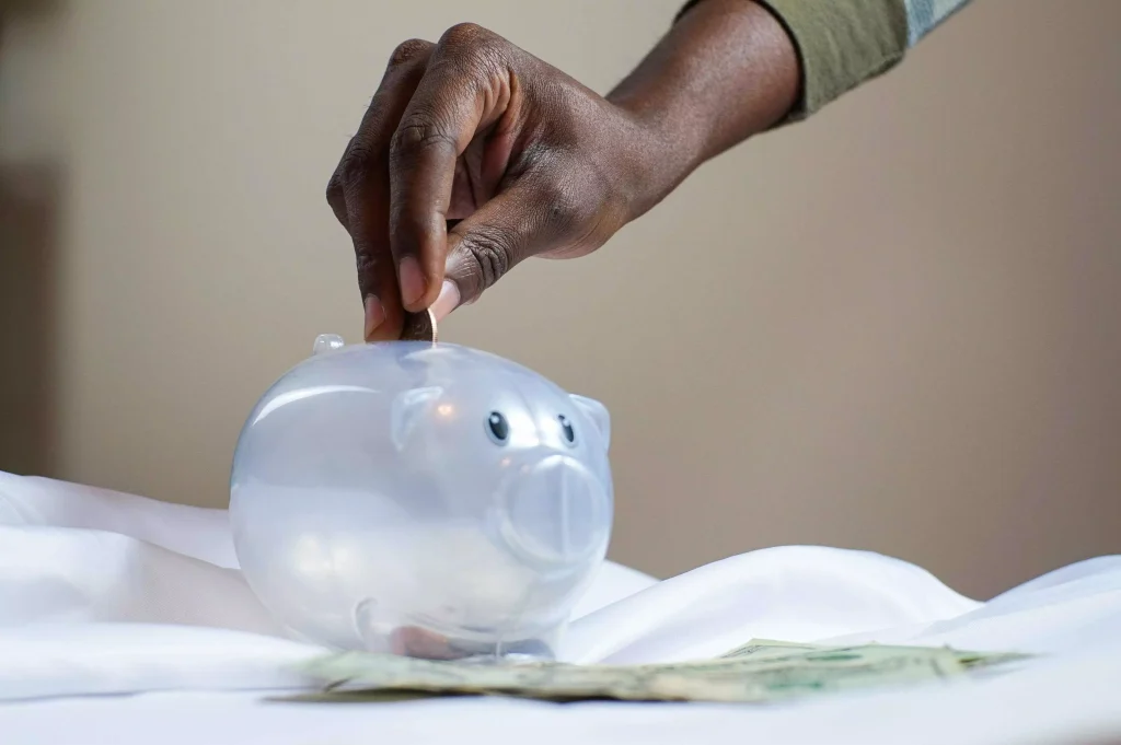 a person putting money in a glass piggy bank