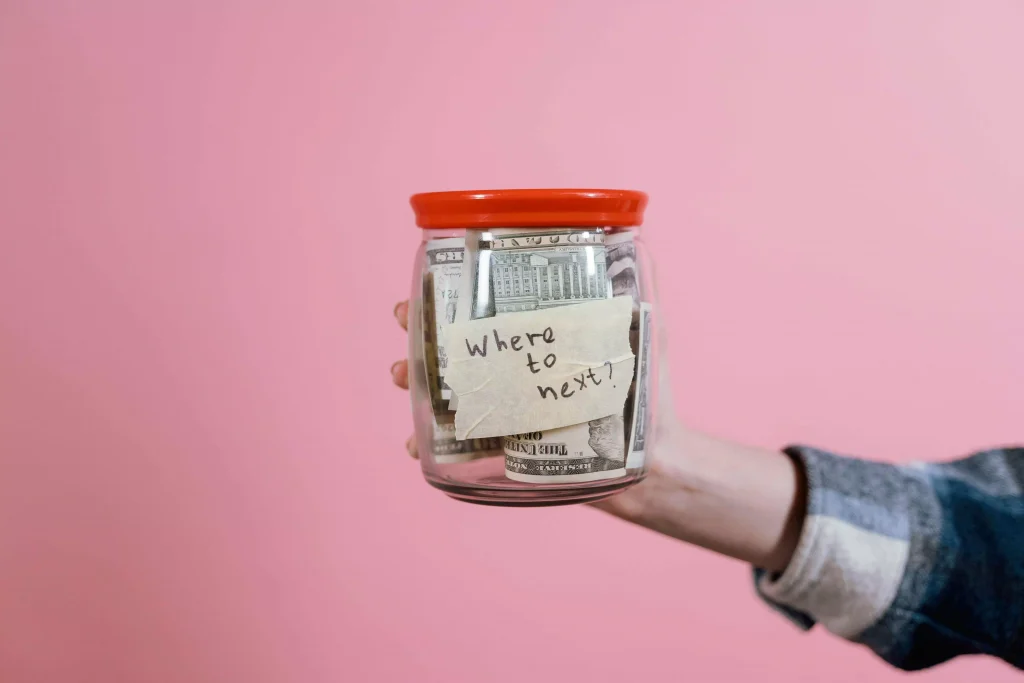 a glass jar with a red lid and a paper on it which says "where to next"