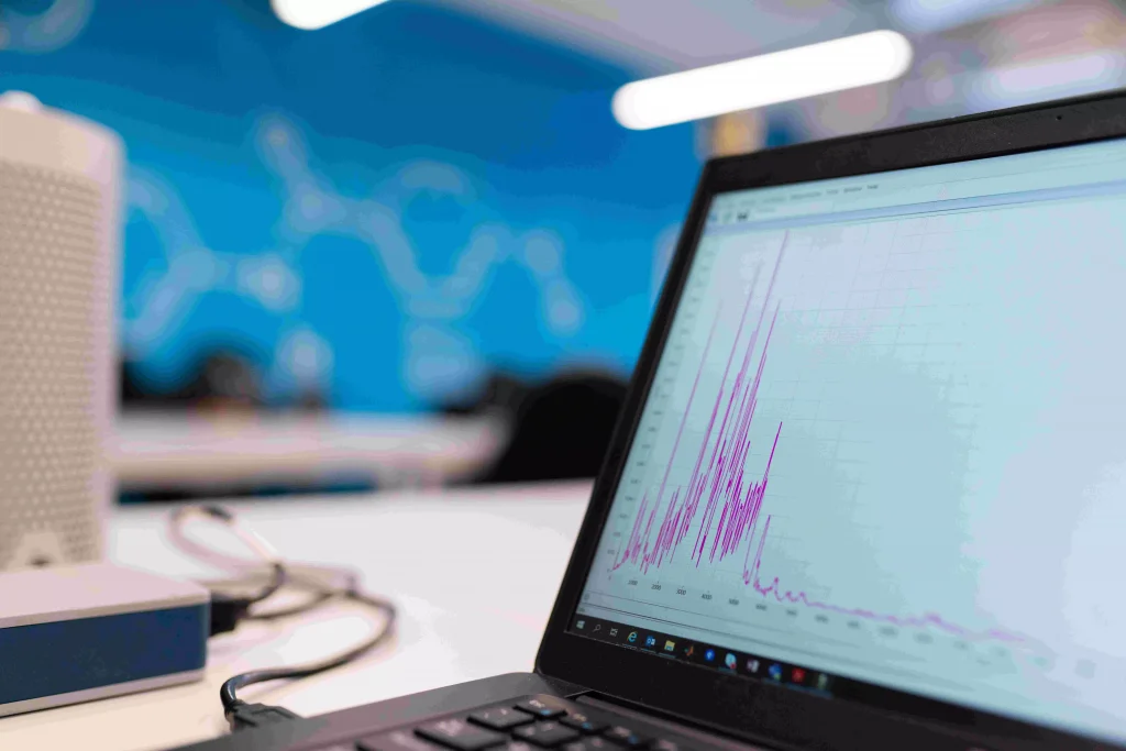 a graph on a laptop screen on a table next to a coffee mug