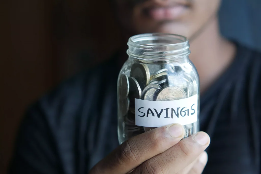 a glass jar with money in it and savings written on it